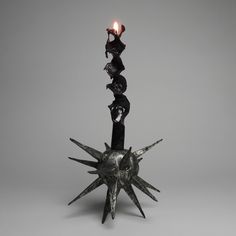 a metal object with three candles on it's top and one candle in the middle