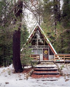 a small cabin in the woods with stairs leading up to it's front door