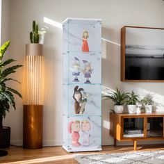 a living room with a television, plants and pictures hanging on the wall in front of it