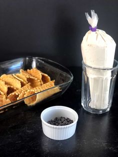 a bowl of ice cream next to some waffles and chocolate chips on a table