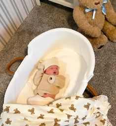 a baby laying in a crib next to a teddy bear