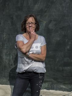 a woman standing in front of a chalkboard with her hand on her mouth and looking at the camera