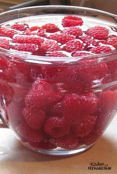 raspberries in a glass bowl on a table