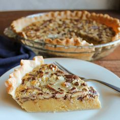 a slice of pecan pie on a plate with a fork next to the pie