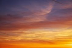 an airplane is flying in the sky at sunset