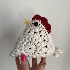 a crocheted chicken ornament is held up by a woman's hand