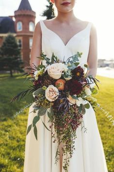 a woman wearing a white dress holding a bouquet in her hand and standing on the grass