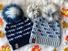 two knitted hats with pom - poms on top of a white blanket