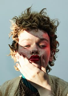 a woman with her face painted red and holding her hands to her mouth as if she is biting into something