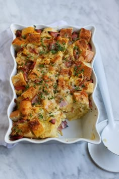 a casserole dish with meat and vegetables in it on a marble counter top