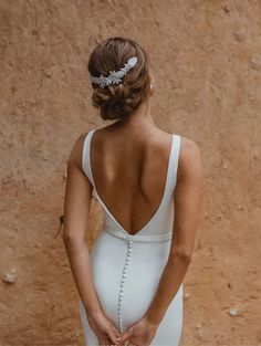 the back of a woman in a white wedding dress holding her hand on her hip