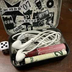 an open suitcase with earbuds and other items in it on a wooden table