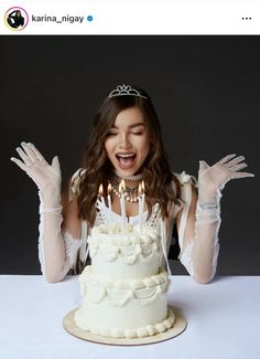 a woman wearing gloves and holding her hands up in front of a cake with lit candles