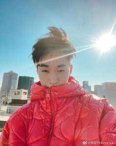 a young man in a red jacket is posing for a photo with the sun shining behind him