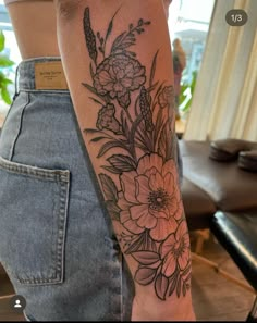 a woman's arm with flowers and leaves tattooed on the back of her body