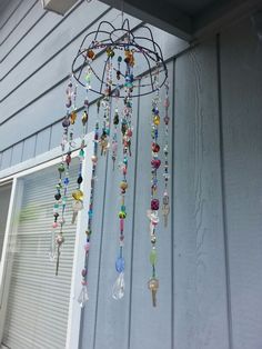 a wind chime hanging from the side of a house with lots of beads on it