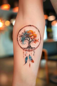 a woman's arm with a tree and feathers tattoo on the left side of her leg