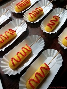 hotdogs with ketchup and mustard on paper plates sitting on a table