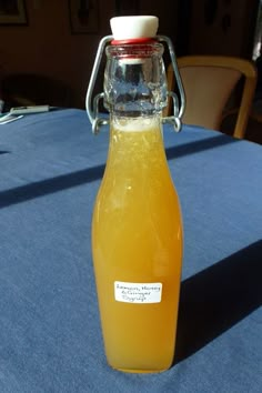 a glass bottle filled with orange juice on top of a blue tablecloth covered table