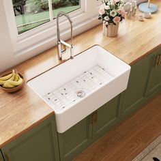 a kitchen sink sitting on top of a wooden counter next to a window with flowers