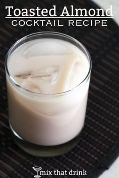 a glass filled with liquid sitting on top of a black tableclothed place mat