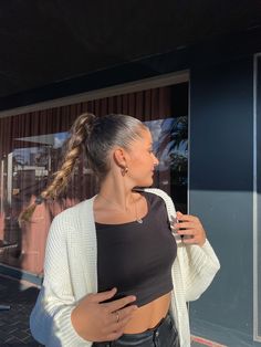 a woman standing in front of a store window with her hand on her hip and looking out the window