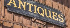 an old sign on the side of a building that says antiques in gold and black