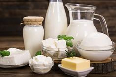 dairy products are arranged on a wooden table, including milk and cottage cheese as well as butter