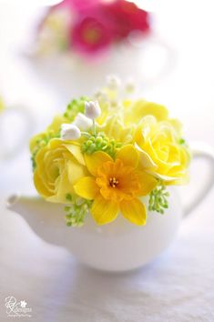 yellow and white flowers in a tea pot