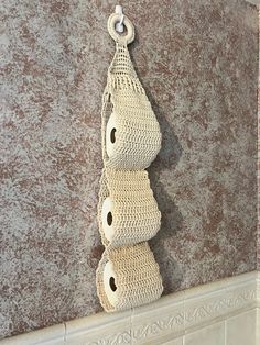 two crocheted toilet paper holders hanging on the wall next to a tiled fireplace