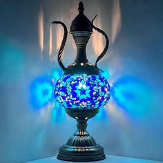 a blue glass vase sitting on top of a table next to a light up wall