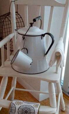 a white tea pot sitting on top of a wooden chair