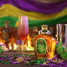 a bottle of alcohol sitting next to a glass filled with liquid and mardi gras beads