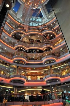 the interior of a large cruise ship with stairs and balconies on each floor