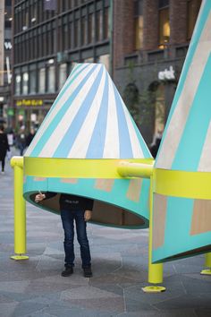 a person hiding behind two large blue and yellow cones