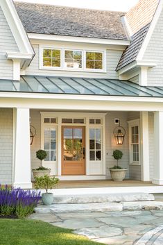 a white house with blue shutters and two potted plants on the front porch