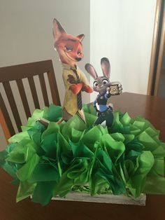 a table topped with green tissue paper and two toy figurines on top of it