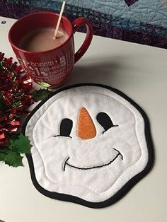 a frosty snowman coaster next to a cup of coffee