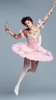 a woman in a pink tutu and ballet outfit holding a wine glass while standing on one leg