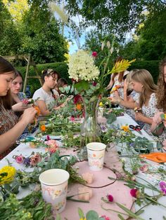 a group of people sitting at a table with flowers in vases and plates on it