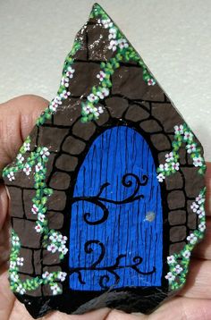 a hand holding a rock with a blue door painted on it