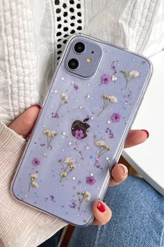 a woman is holding her phone case with flowers on it