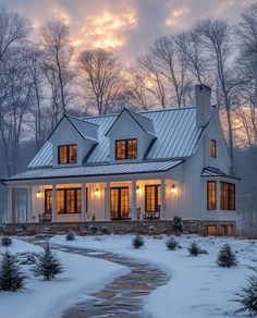 a white house in the middle of winter with snow on the ground and trees around it