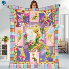 a woman holding up a blanket with tinkerbells and flowers in the background