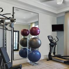 a gym with exercise balls and machines in front of a flat screen tv mounted on the wall