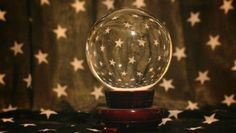 a snow globe sitting on top of a wooden stand in front of a curtained background