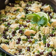 a bowl filled with rice, beans and cilantros next to a lime wedge