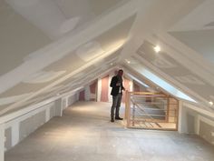 a man standing in the middle of a room with white walls and exposed ceilinging