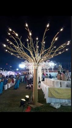 an outdoor event with many tables and lights on the trees in the middle of it