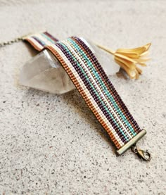 a beaded bracelet sitting on top of a piece of glass next to a flower